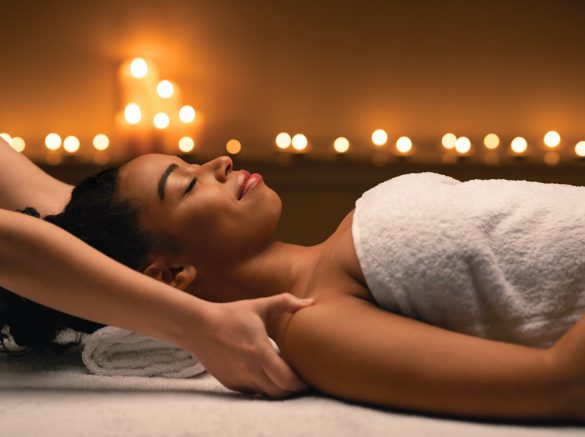 Female therapist hands massaging african lady shoulders at spa