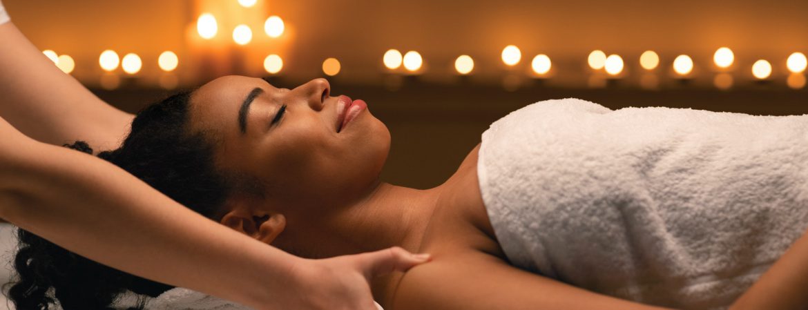 Female therapist hands massaging african lady shoulders at spa