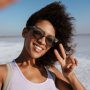 Image of african american woman gesturing peace sign and taking selfie