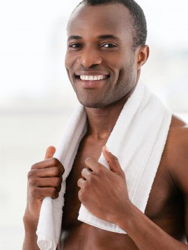 Man after workout. Handsome young African man with towel on shoulders looking at camera and smiling